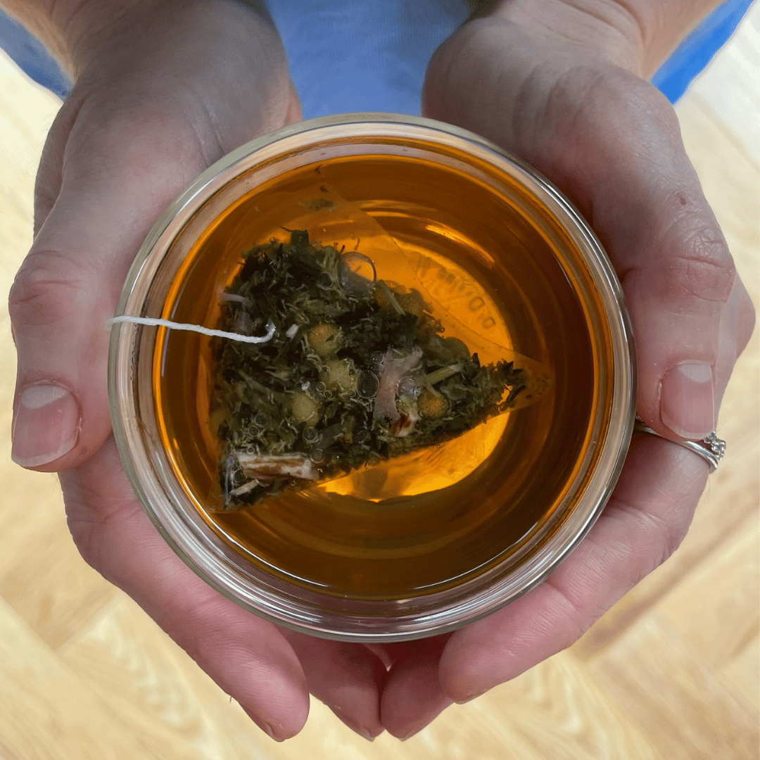Tea cup and saucer, with a brewed cup of whole leaf tea in it and pack of tea next to it