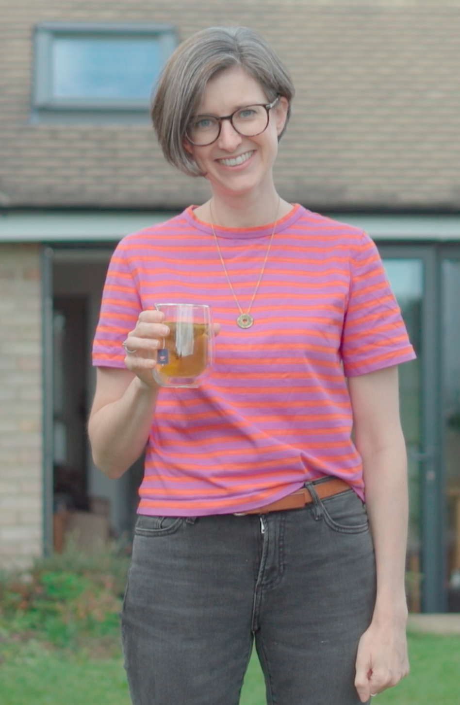 Bethan, founder of HotTea Mama, with a cup of tea stood outside her house, wondering if she's menopausal
