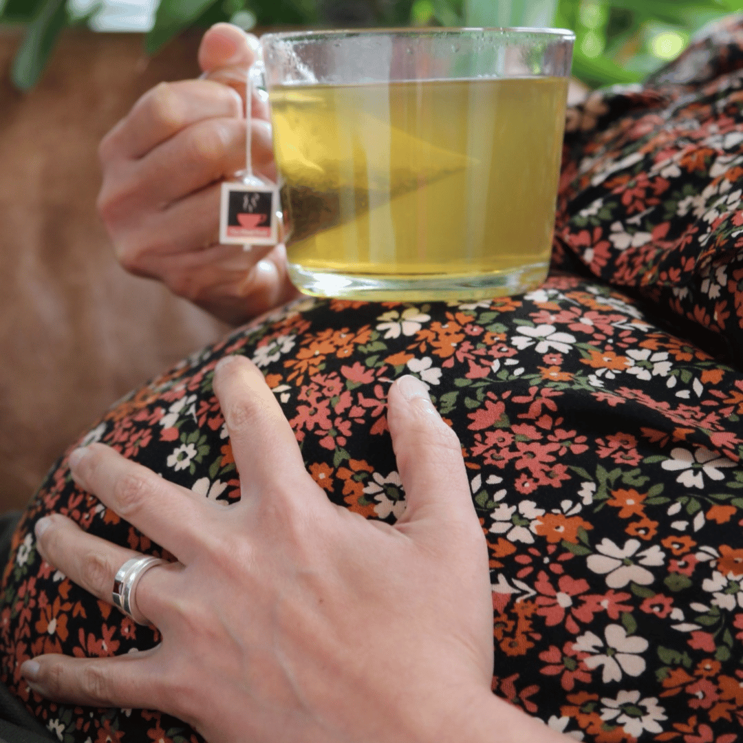 Pregnant woman in patterned top, holding a cup of The Final Push raspberry leaf tea