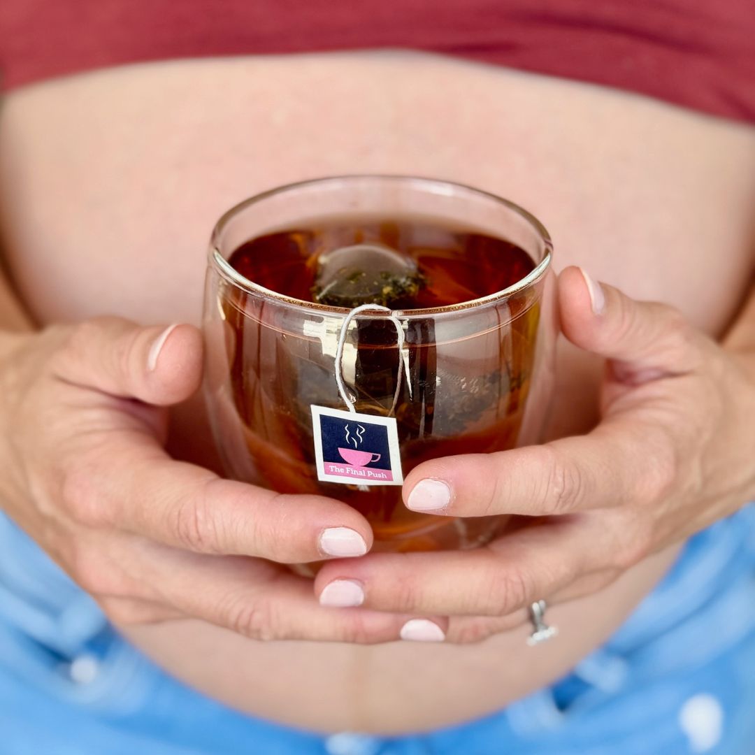 Close up shot of pregnant belly and ladies hands holding a cup of HotTa Mama The Final Push raspberry leaf tea
