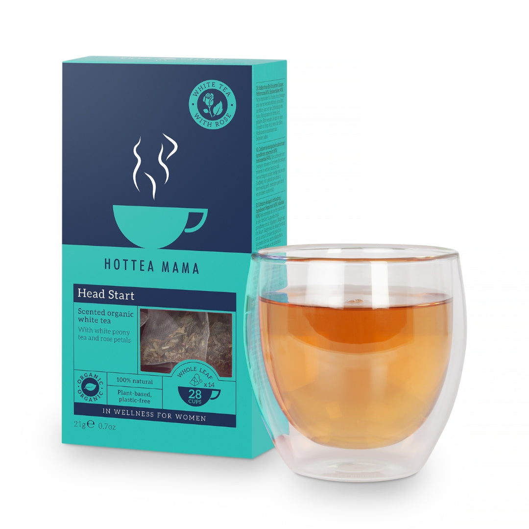 A brewed cup of HotTea Mama Organic Head Start white tea and rose, with the turquoise and navy box behind it. This tea can support tiredness as it has a high caffeine and L-theanine level, great for new mums, perimenopausal women and any under stress and struggling to sleep.