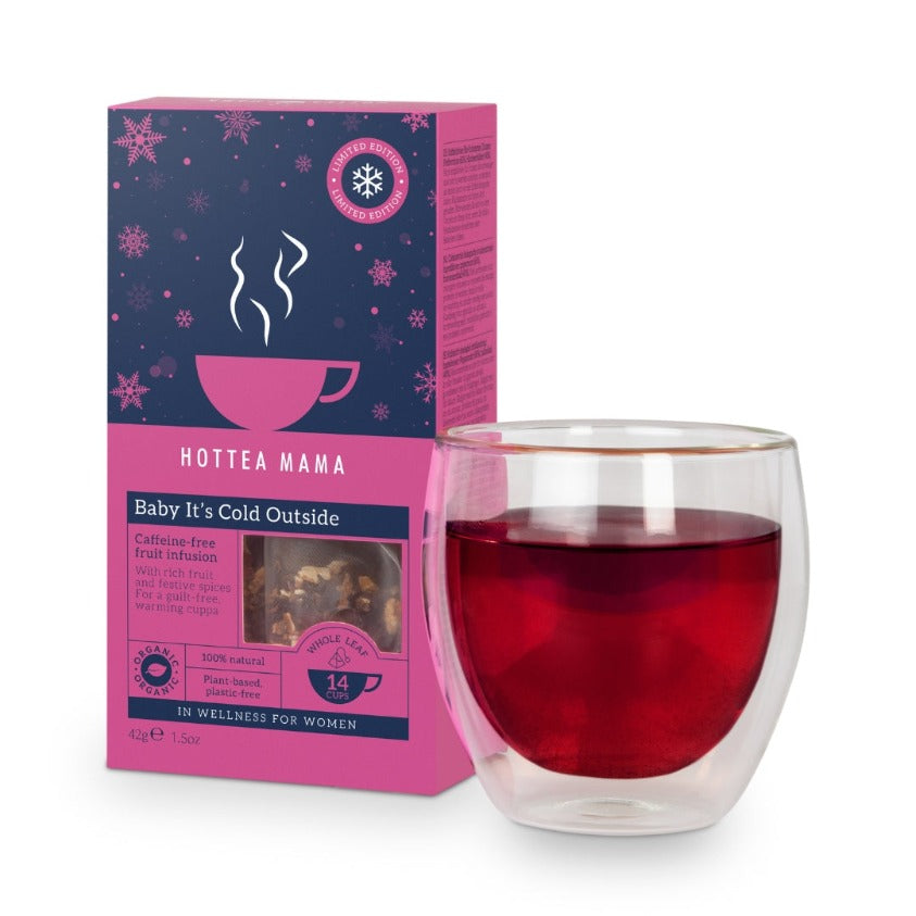 Pack of Baby It's Cold Outside Organic Christmas Tea sat next to a brewed cup of the fruit tea