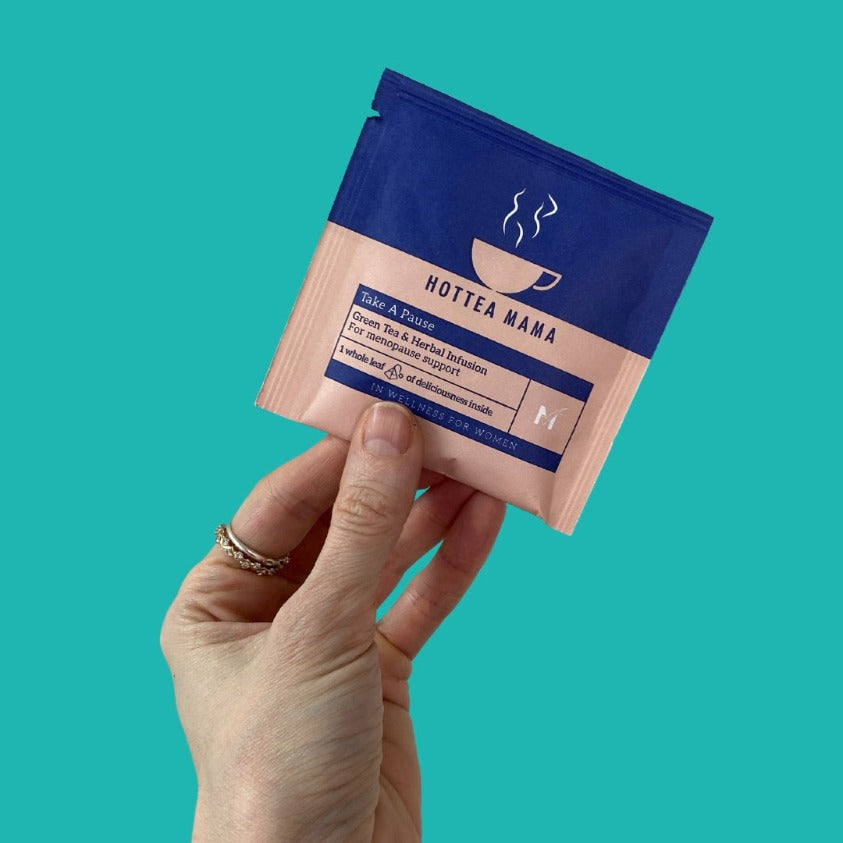 A sample of Take A Pause menopause tea held against a turquoise background
