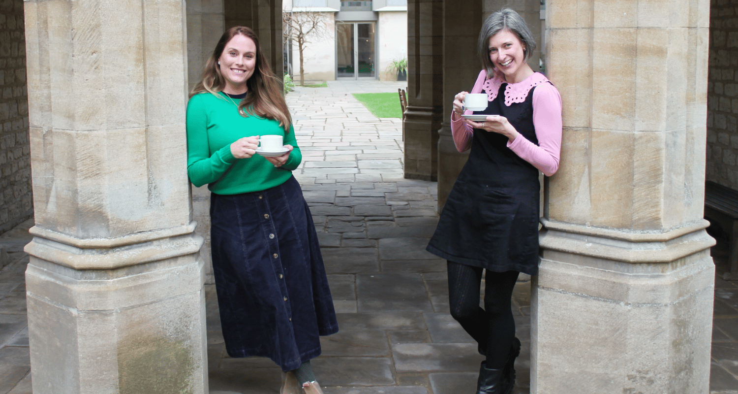 Image of HotTea Mama co-founders Kate & Bethan standing drinking cups of tea together in an Oxford College courtyard