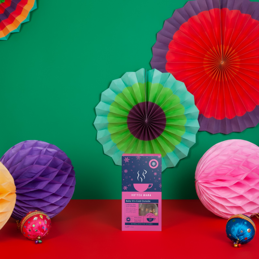 Pack of Baby It's Cold Outside organic Christmas tea surrounded by Christmas decorations