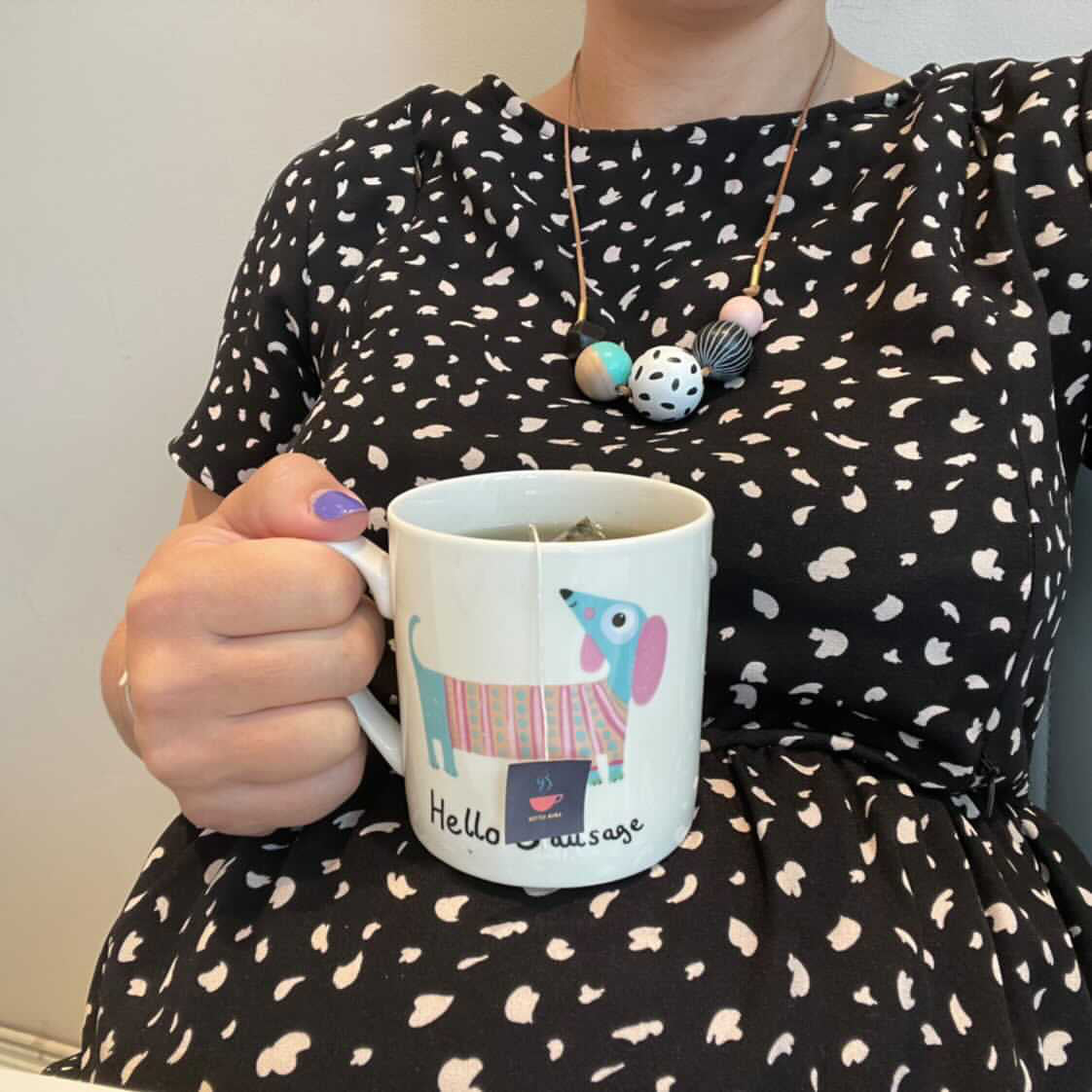 Pregnant lady in spotty dress, sitting a tea cup with HotTea Mama tea on her bump