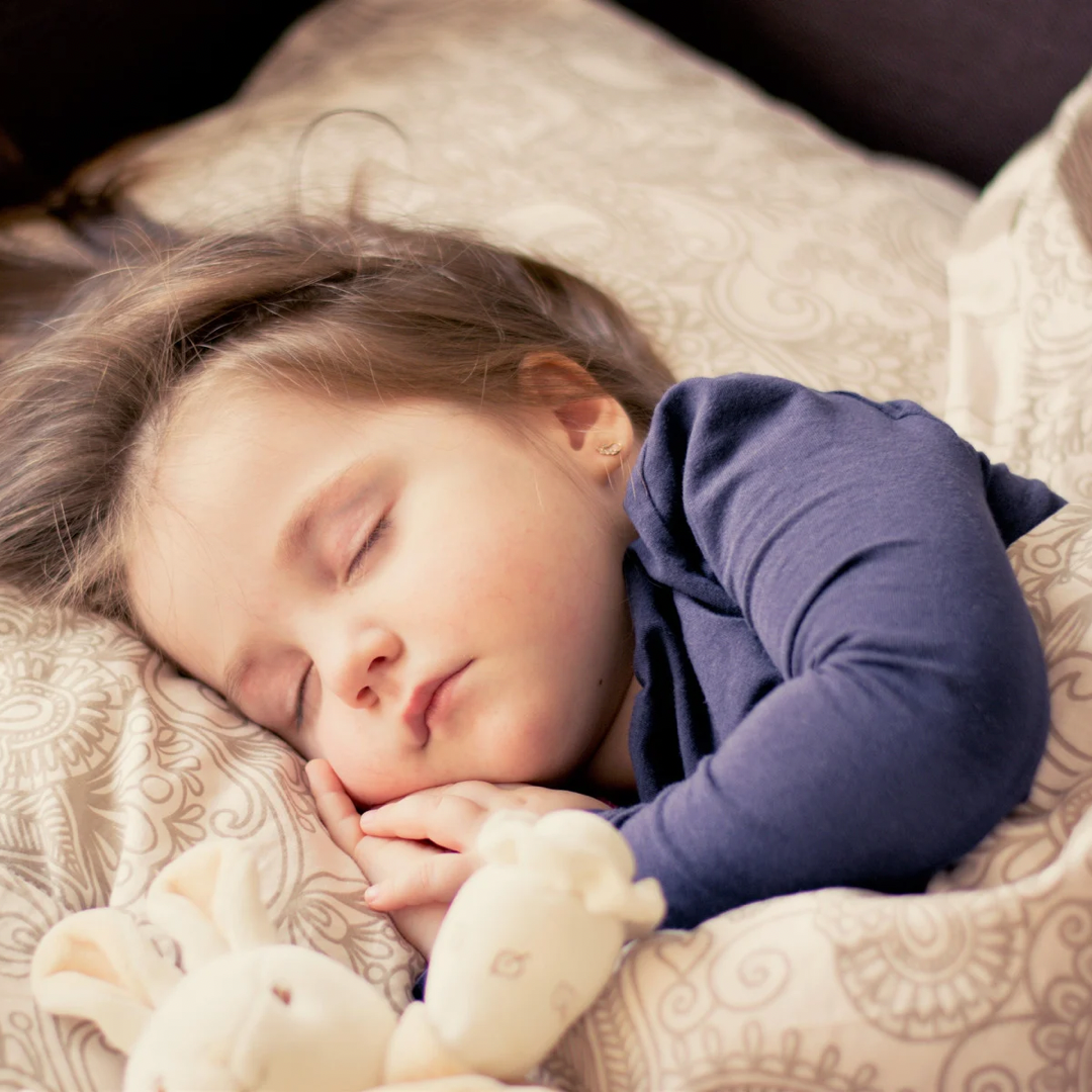 sleeping baby with teddy bear in bed