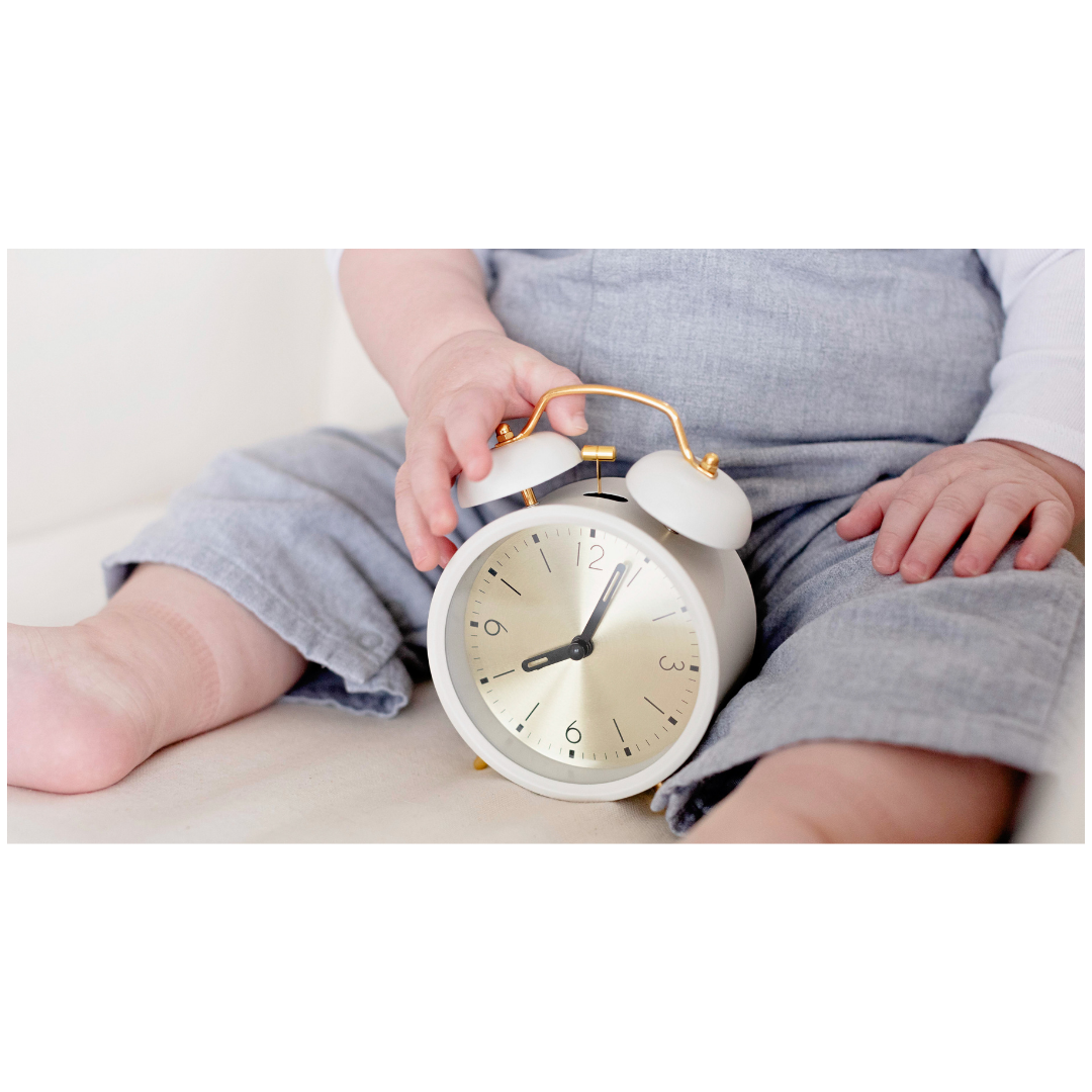 Close up of babies legs, arms and tummy, with clock in between babies legs