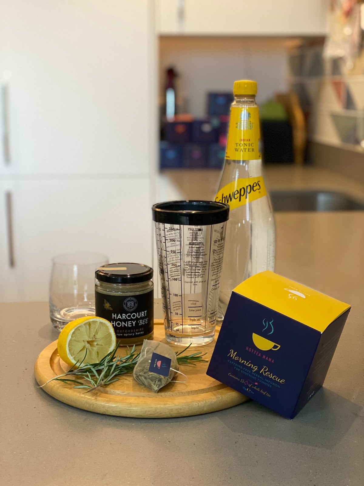 Ingredients for mocktail on kitchen side - tonic water, cocktail mixer, honey, lemon, Morning Rescue Tea