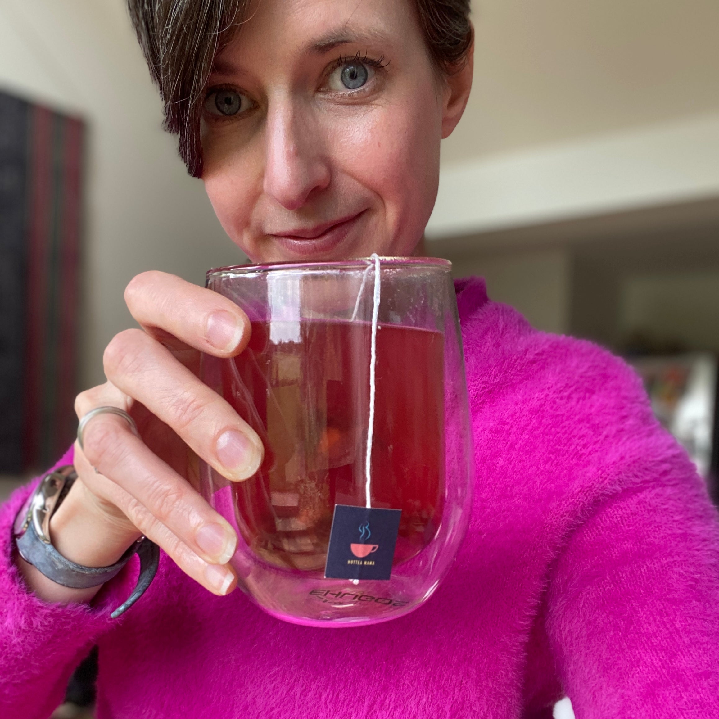 Woman in pink jumper holding glass cup with mulled tea inside