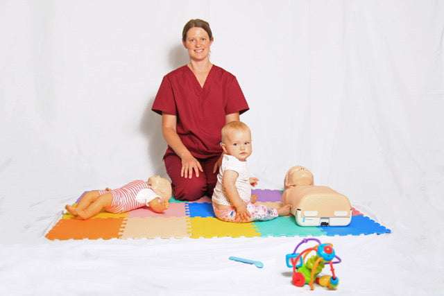 Lady in first aid outfit sat with little girl on mat