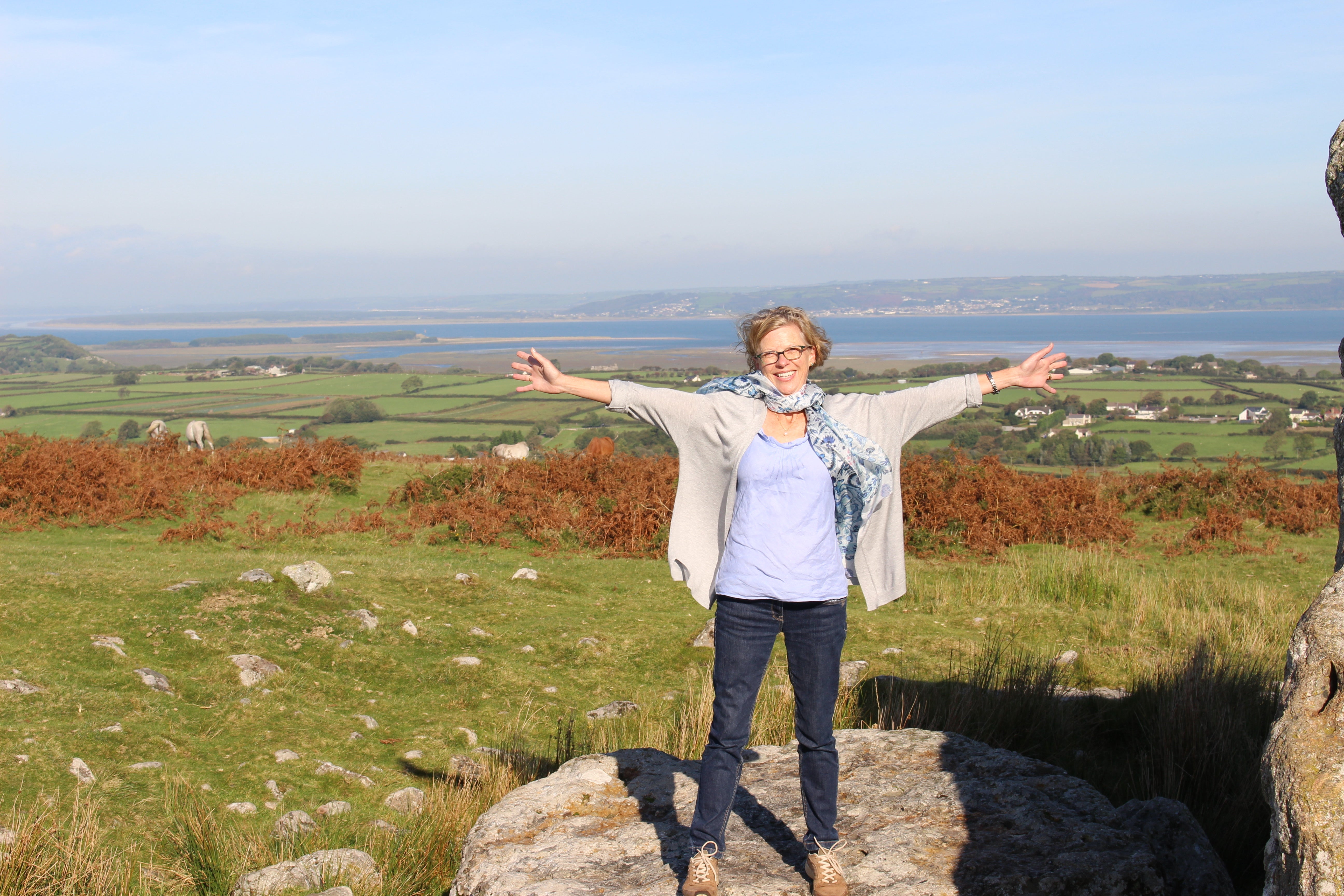 Woman stood on rock in open plain with countryside around her