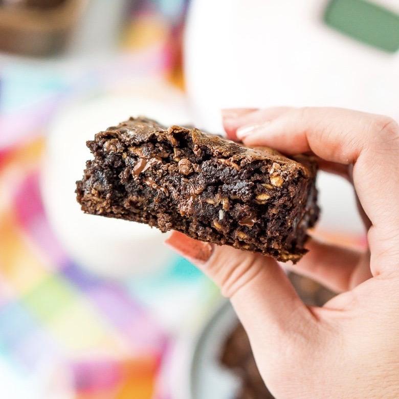 Hand holding gooey brownie up close