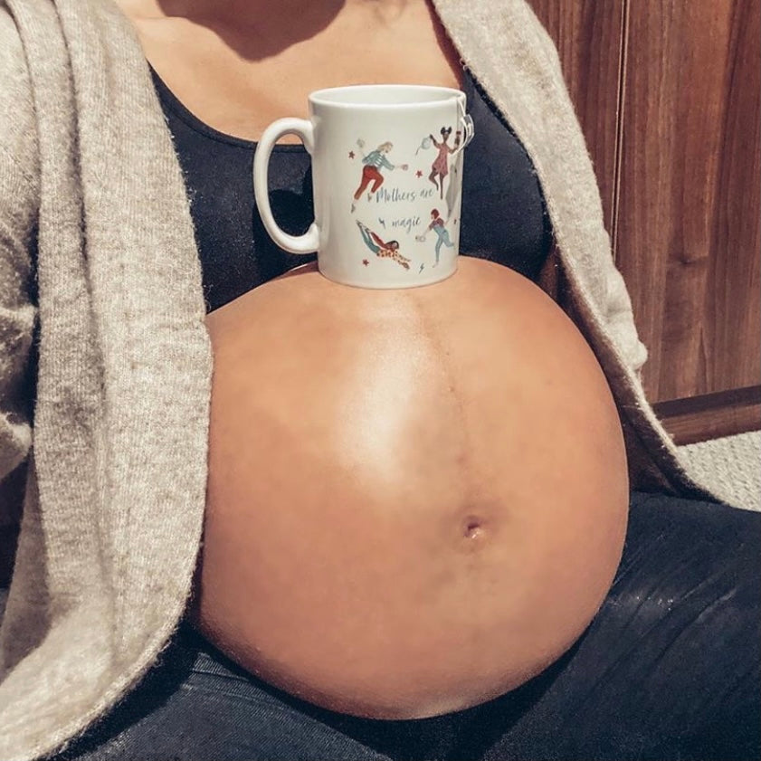 Large pregnant baby bump with mug balancing on top of it