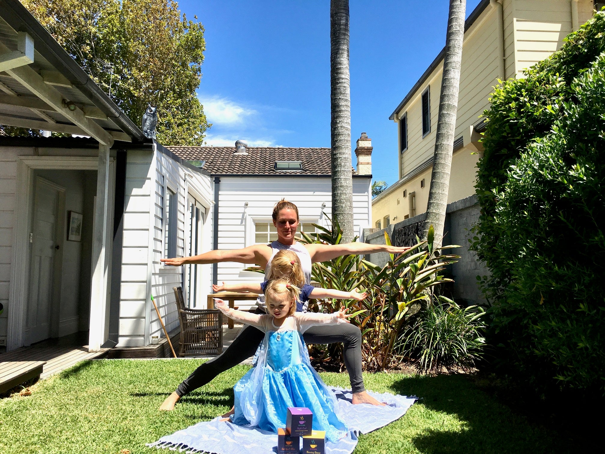 Woman and 2 little girls doing yoga in the garden