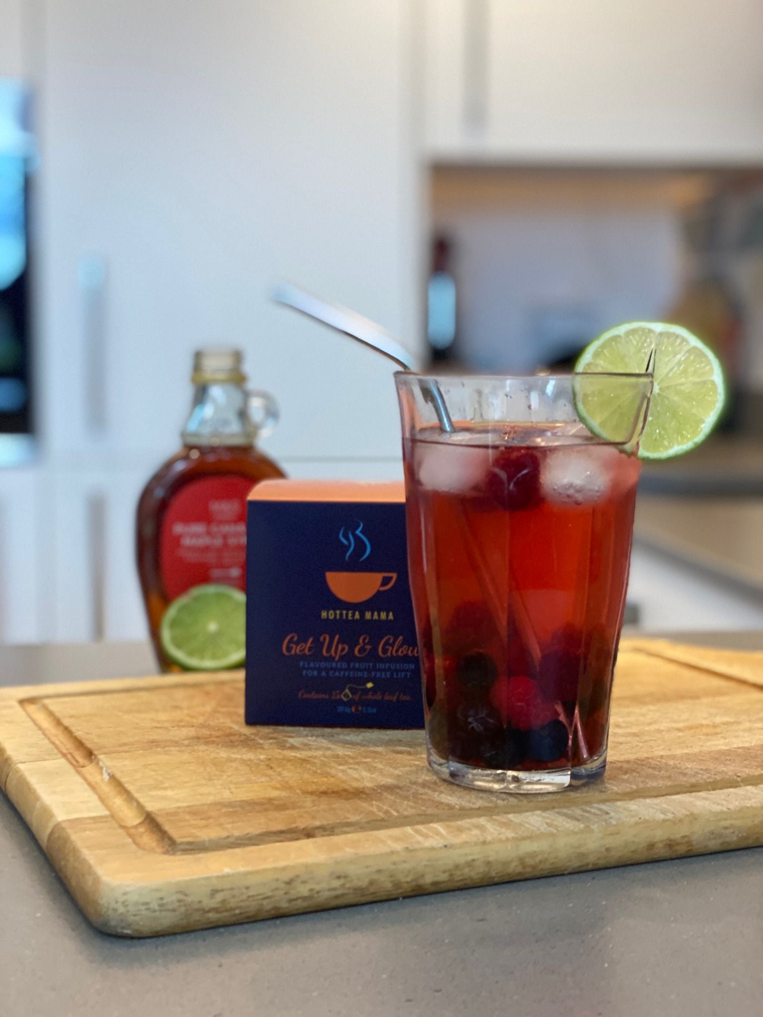 Get Up & Glow Maple Iced Tea Mocktail in a glass with a lime wedge on kitchen side