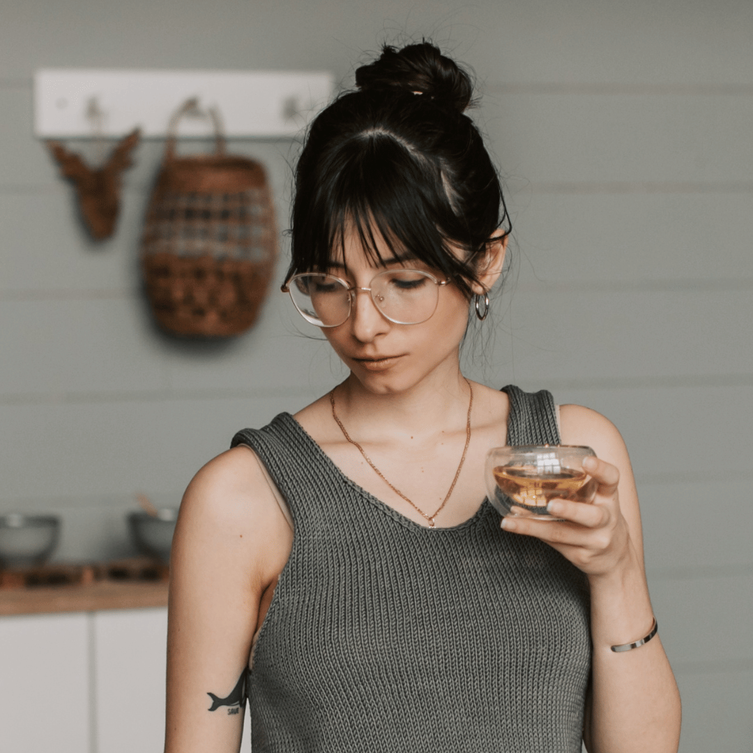 Image of a woman thinking holding a cup of herbal tea