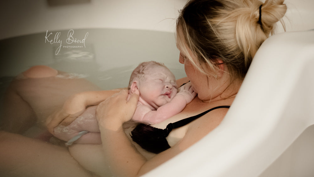 Woman in bath with baby who has just been born via water birth