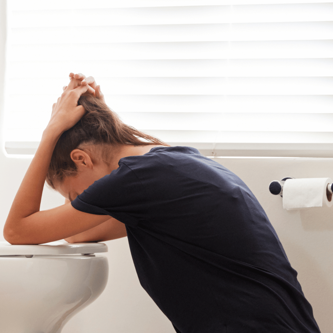 Woman bending over the toilet suffering from pregnancy sickness