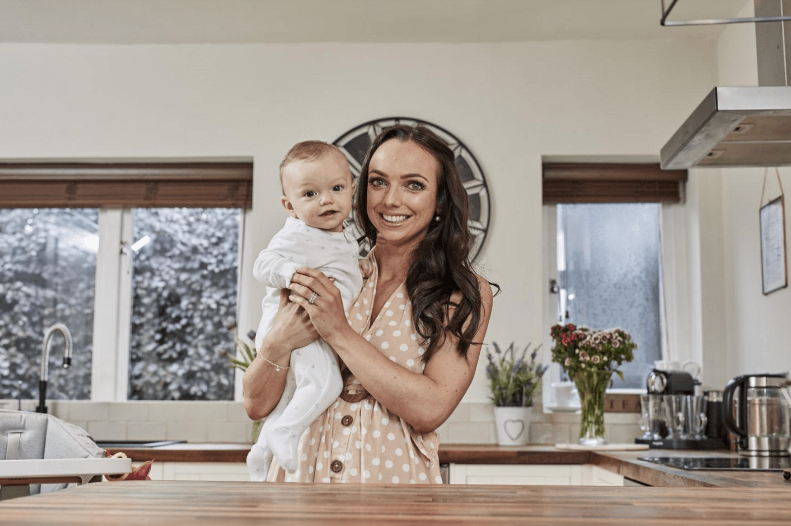 Nicola from Mummy Nutrition, holding her baby boy, stood in a kitchen