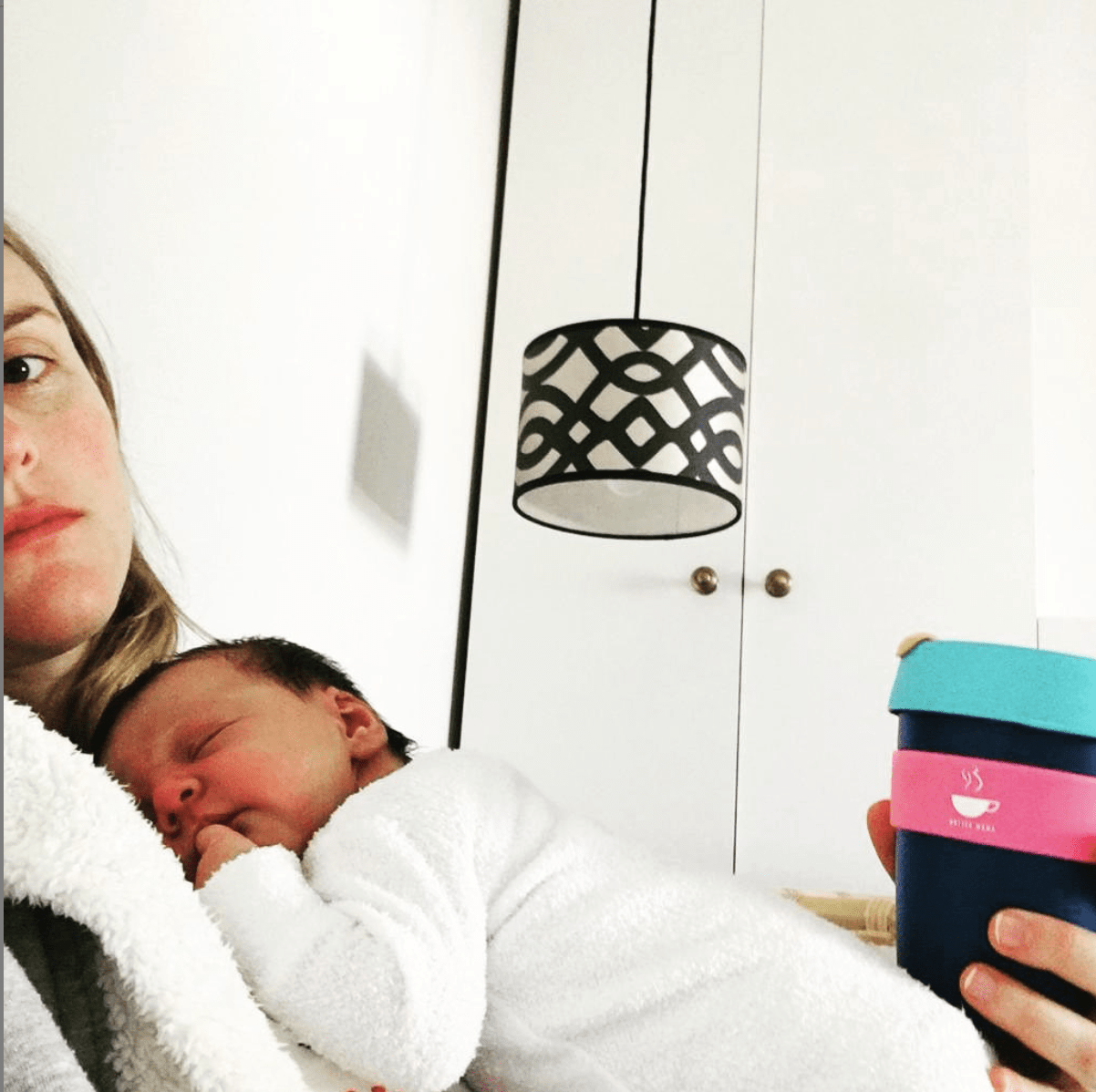 Mum in bed with newborn baby on her chest, looking tired