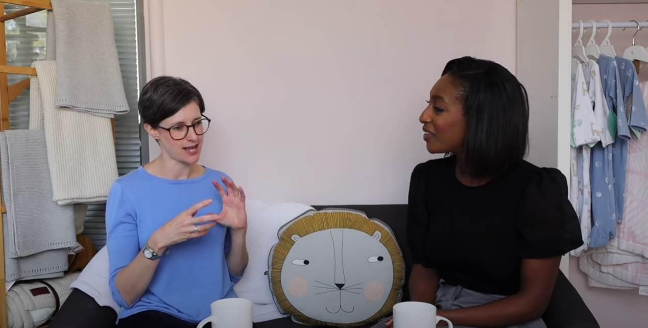 2 women sat on a sofa talking, with tea cups in front of them