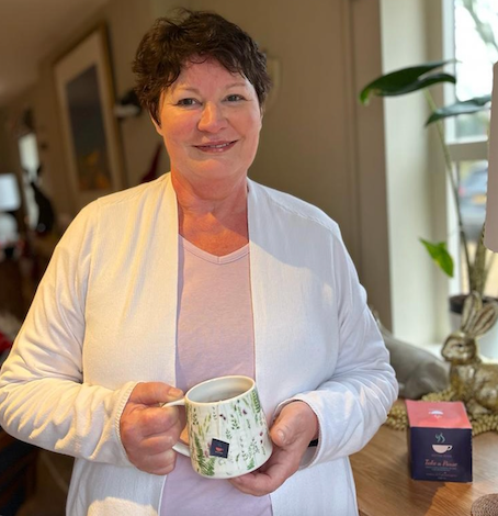 Menopausal woman standing, drinking a cup of Take A Pause menopause tea