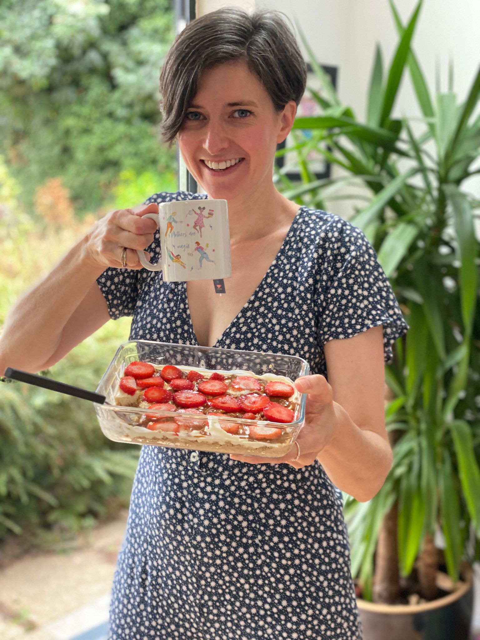 Woman holding dish of overnight oaty cheesecake and a cup of tea