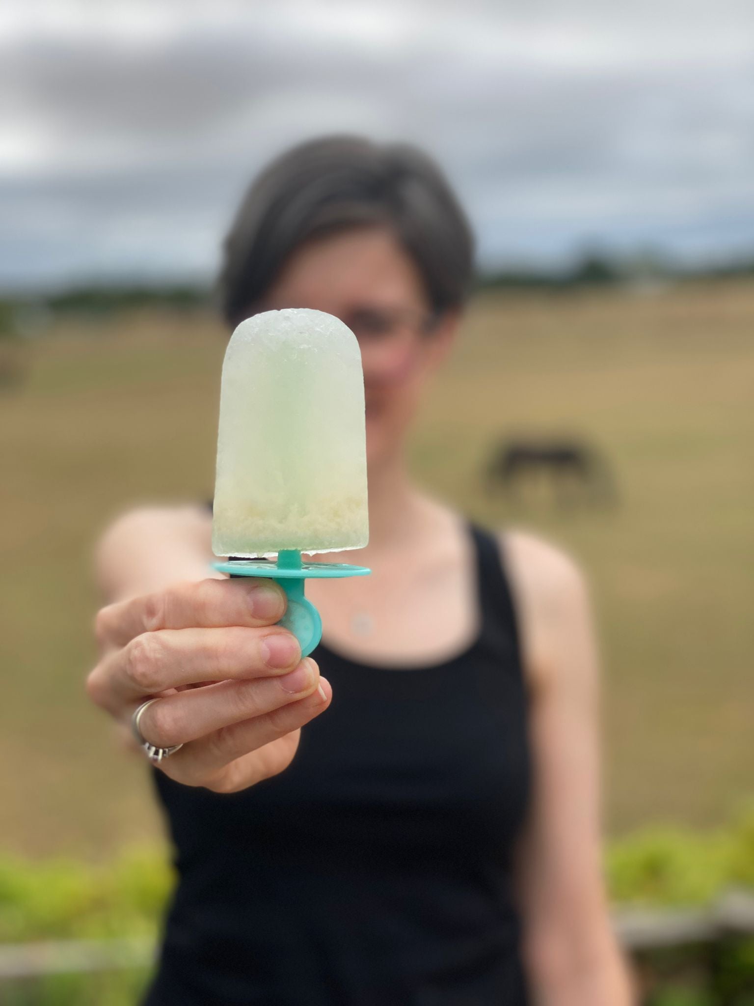 Woman outside holding ice lolly up to camera