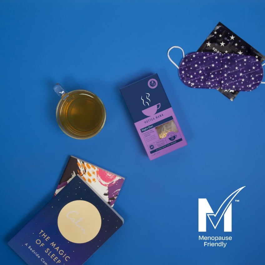 Flat lay image of Night Owl herbal tea on blue background surrounded by sleep mask, sleep books and a brewed cup of calming tea
