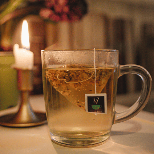 Photograph of a glass cup with Night Owl brewed in candle light relaxed setting