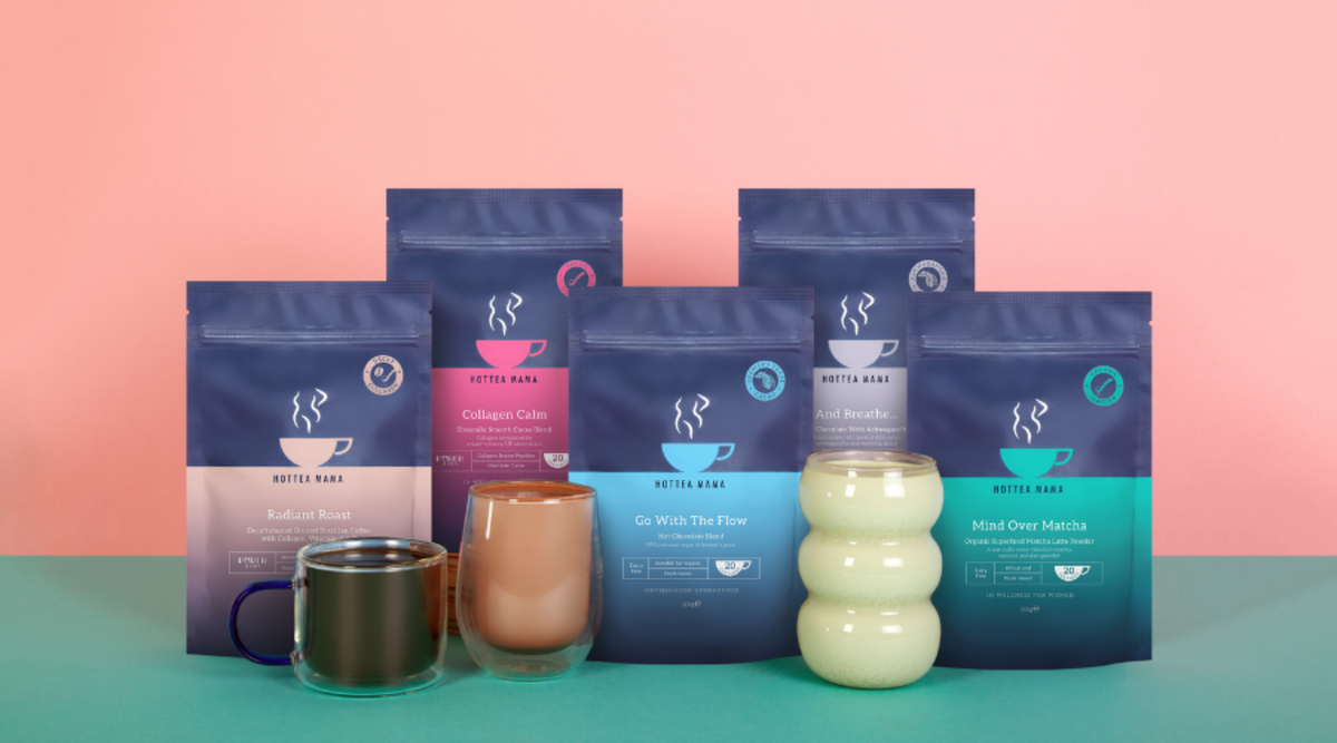 Collection of coffee packaging with mugs and a candle on a pink and green gradient background